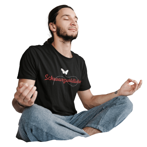 mann meditierend auf dem boden mit schwarzem shirt mit logo schwarzwaldliebe