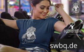 frau sitzend auf dem sofa mit blauem t-shirt mit logo schwarzwald braut mit bollenhut