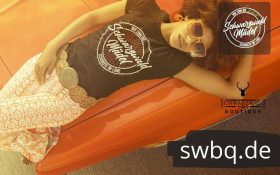 frau mit braunem tshirt liegend mit sonnebrille mit design schwarzwald maedel