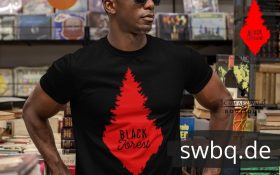mann mit sonnenbrille in einem schallplatten laden mit tshirt mit desing rote schwarzwald tanne