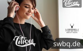 frau mit kopfhoerern und schwarzem langarm shirt mit titisee design