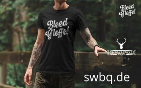 mann mit tatoos auf der bruecke mit schwarzem t-shirt mit design bleed gloffe alemannischer spruch