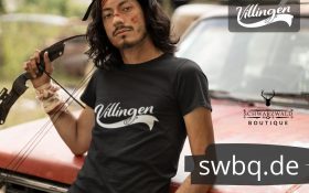 mann mit boden vor einem auto mit schwarzem tshirt mit villingen design