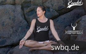 frau sitzen auf steinen in einer yoga pose mit schwarzem tank top mit kandel